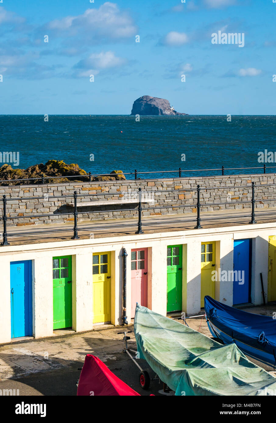 North Berwick Yacht Club überdachte Boote im Hafen und bunten Reihe von Türen. Bass Rock und Leuchtturm am Horizont, Schottland, Großbritannien Stockfoto