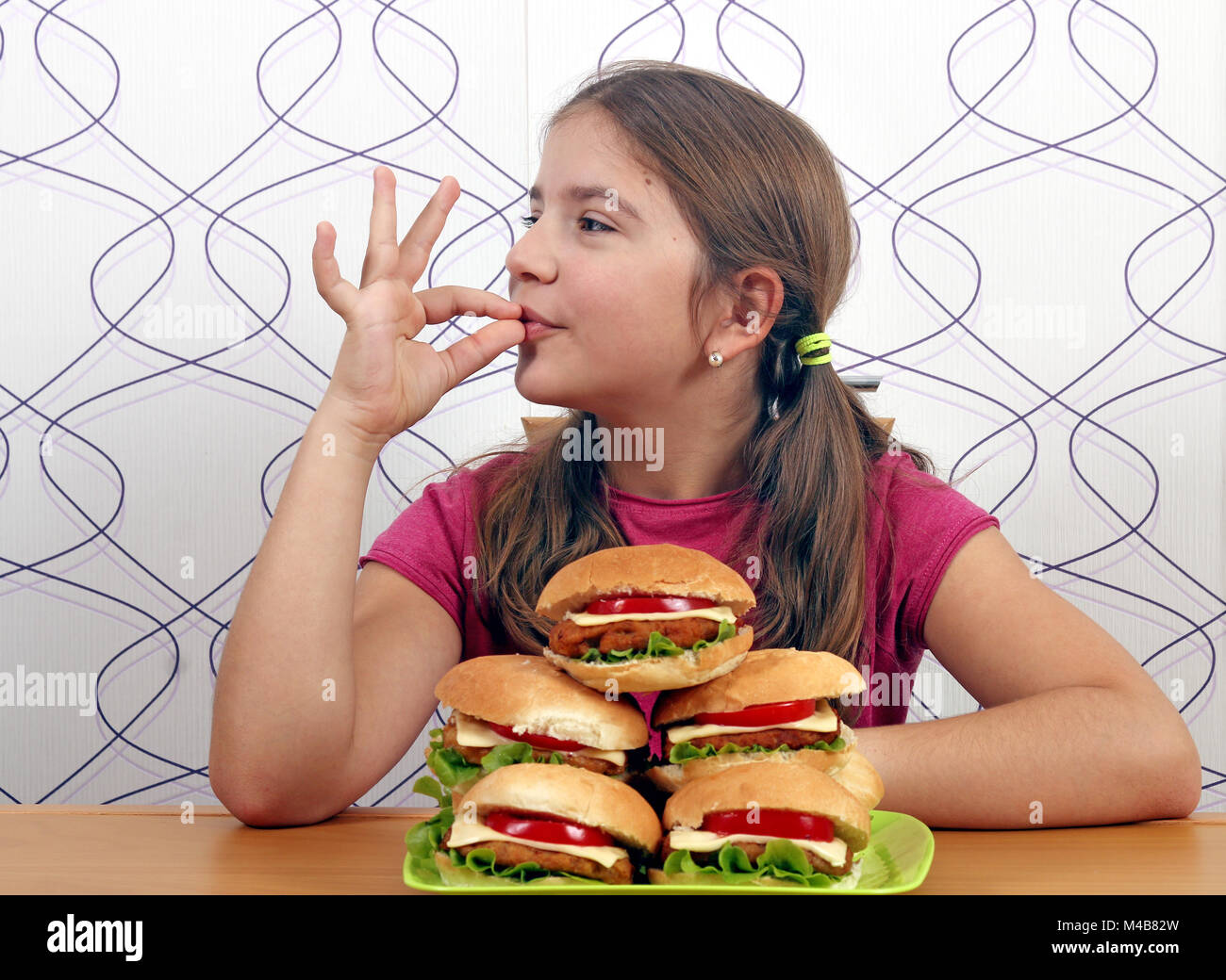 Glückliche kleine Mädchen mit Hamburger und ok Handzeichen Stockfoto