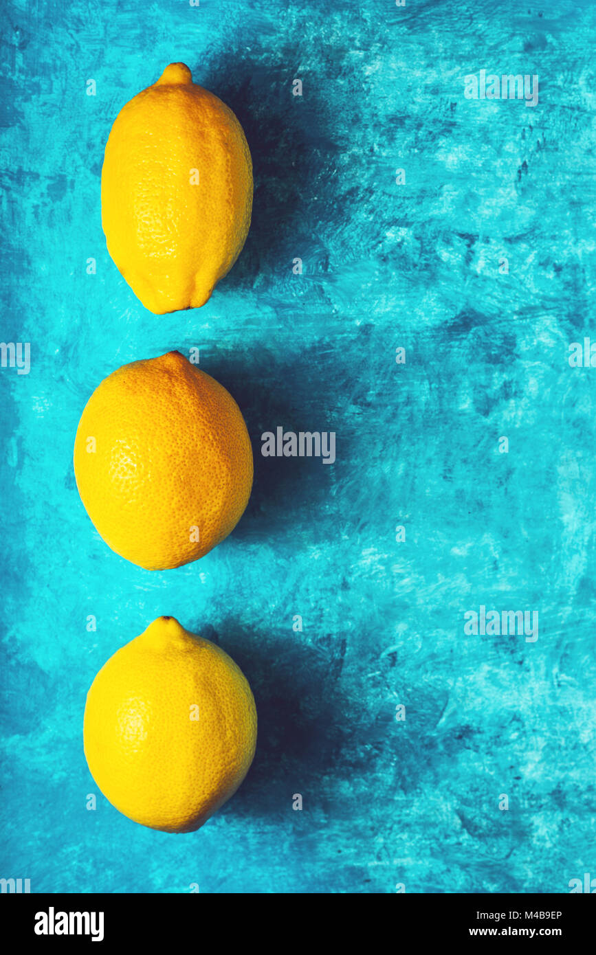 Gelbe Zitronen auf dem blaugrünen Hintergrund vertikale Stockfoto