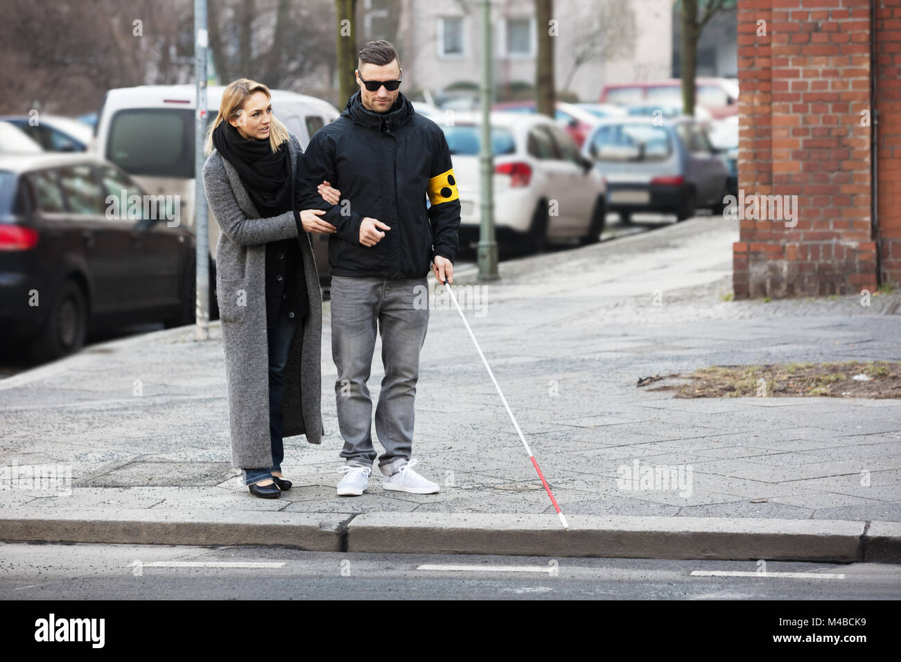 Junge Frau die Unterstützung blinder Mann mit weißem Stick auf der Straße Stockfoto