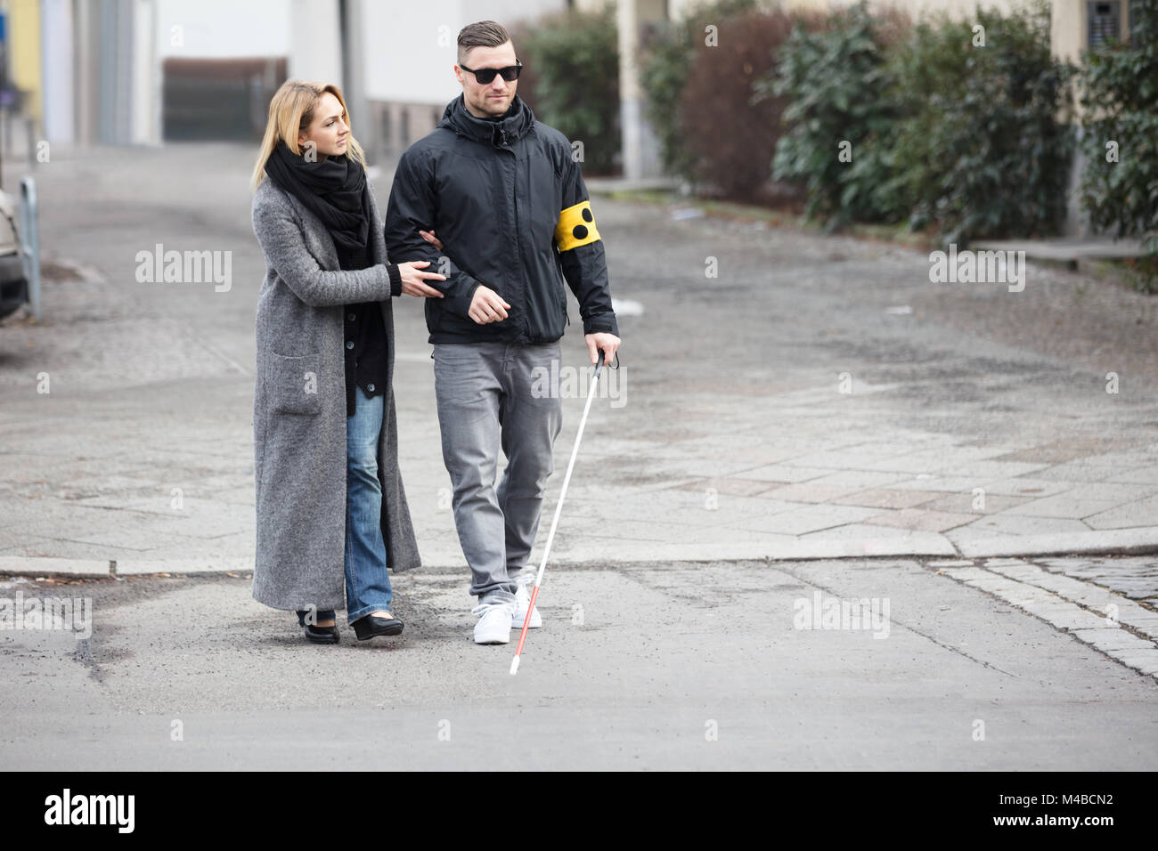 Junge Frau die Unterstützung blinder Mann mit weißem Stick auf der Straße Stockfoto