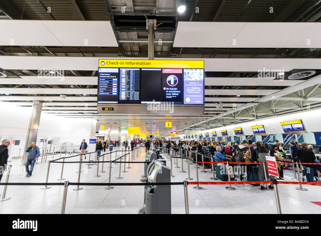 England, Heathrow Terminal 4. Leute anstellen an der Internationale Abflüge Schreibtische in der Kontrolle der mit Gepäck. Interieur. Nacht. Stockfoto