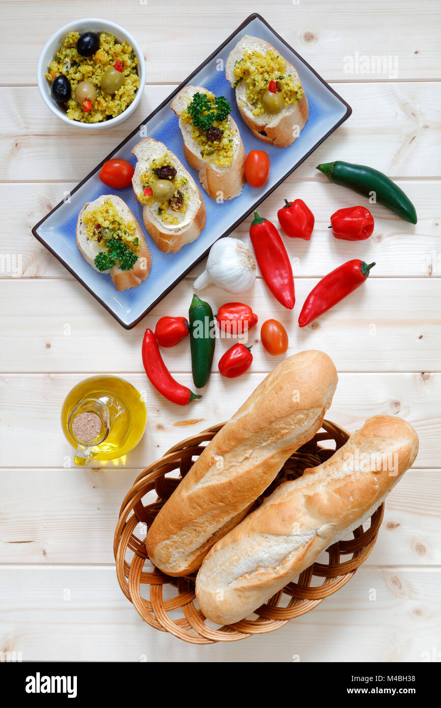 Brötchen im Korb mit Knoblauch und Olivenöl auf hellem Holz Tisch Stockfoto