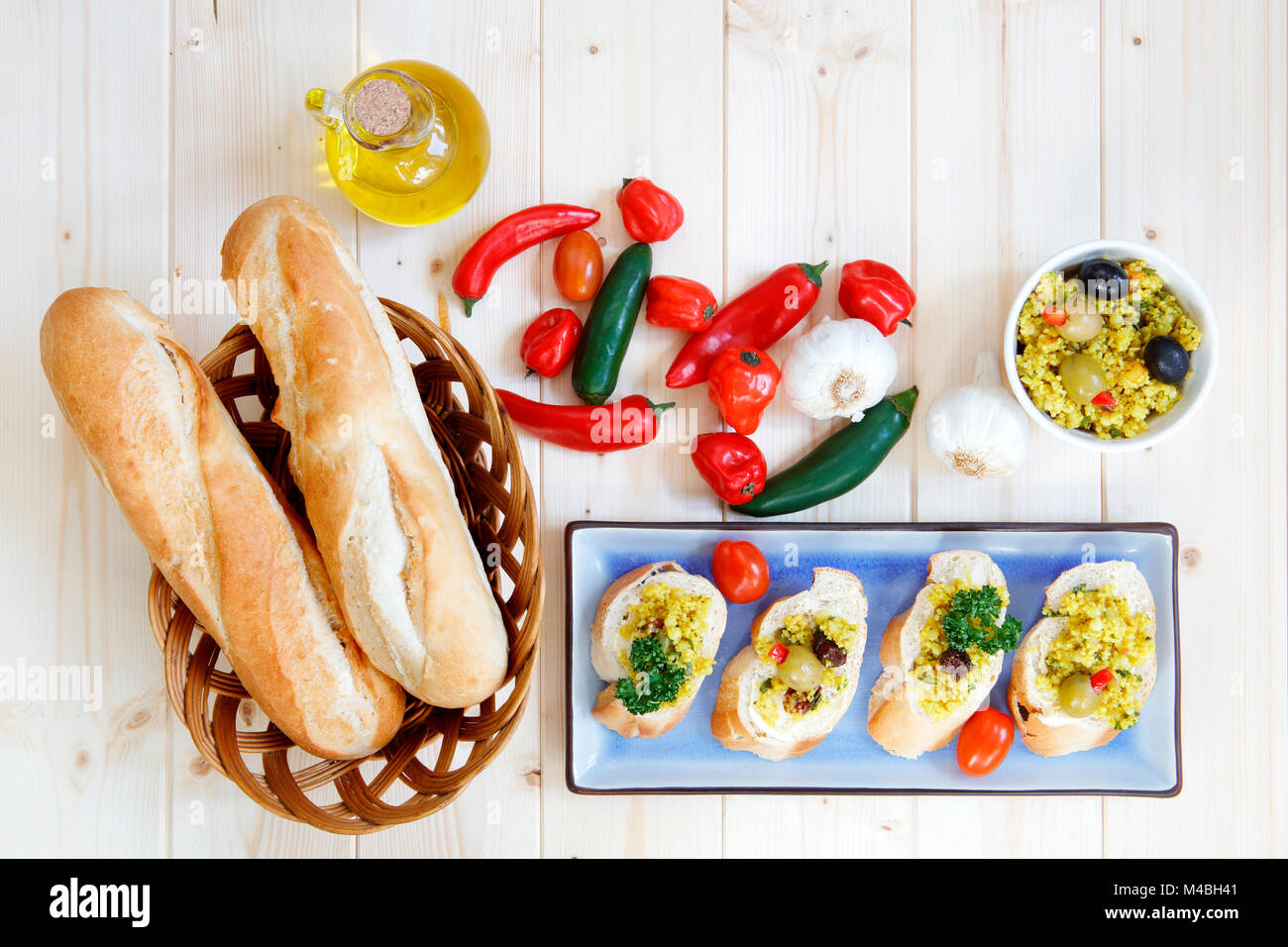 Brötchen im Korb mit Knoblauch und Olivenöl auf hellem Holz Tisch Stockfoto