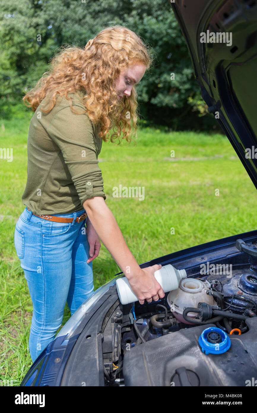 Niederländische Mädchen füllt Auto Kühlsystem mit Kühlmittel Stockfoto
