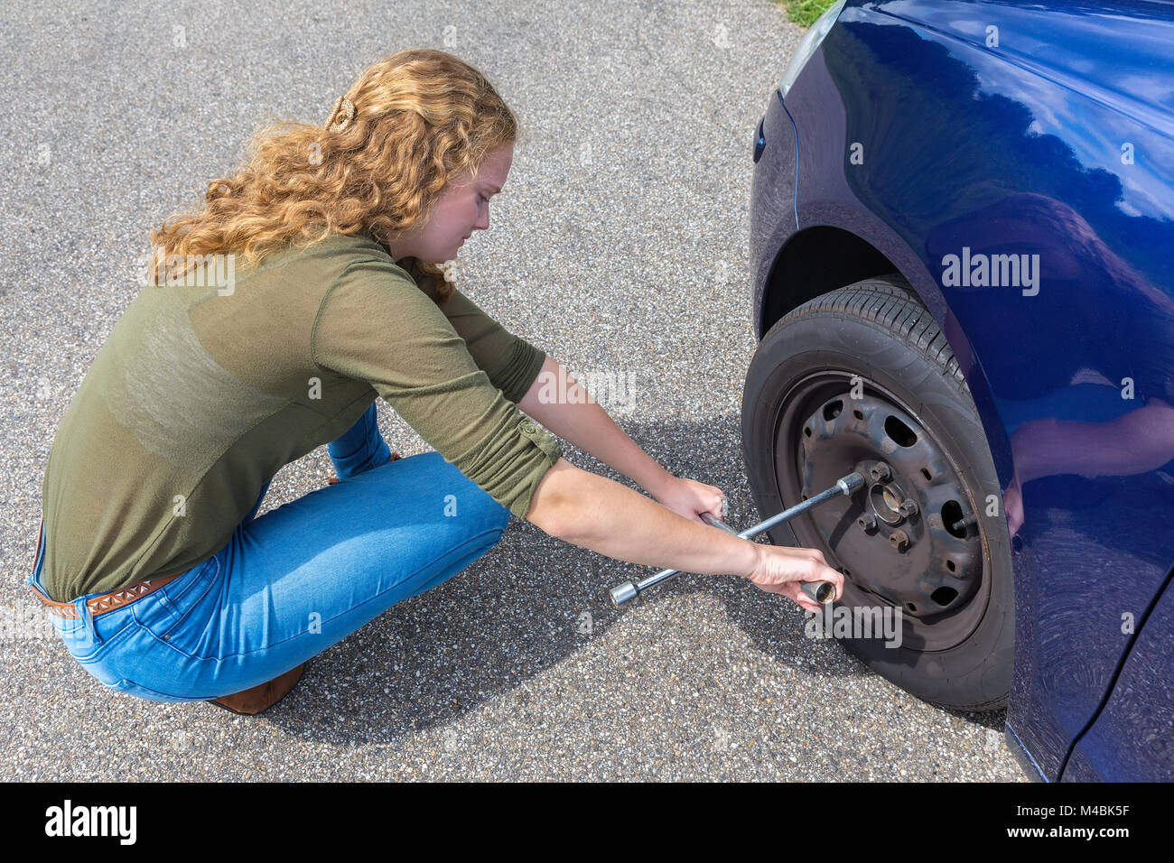 Junge holländische Frau ändern Autoreifen auf der Straße Stockfoto