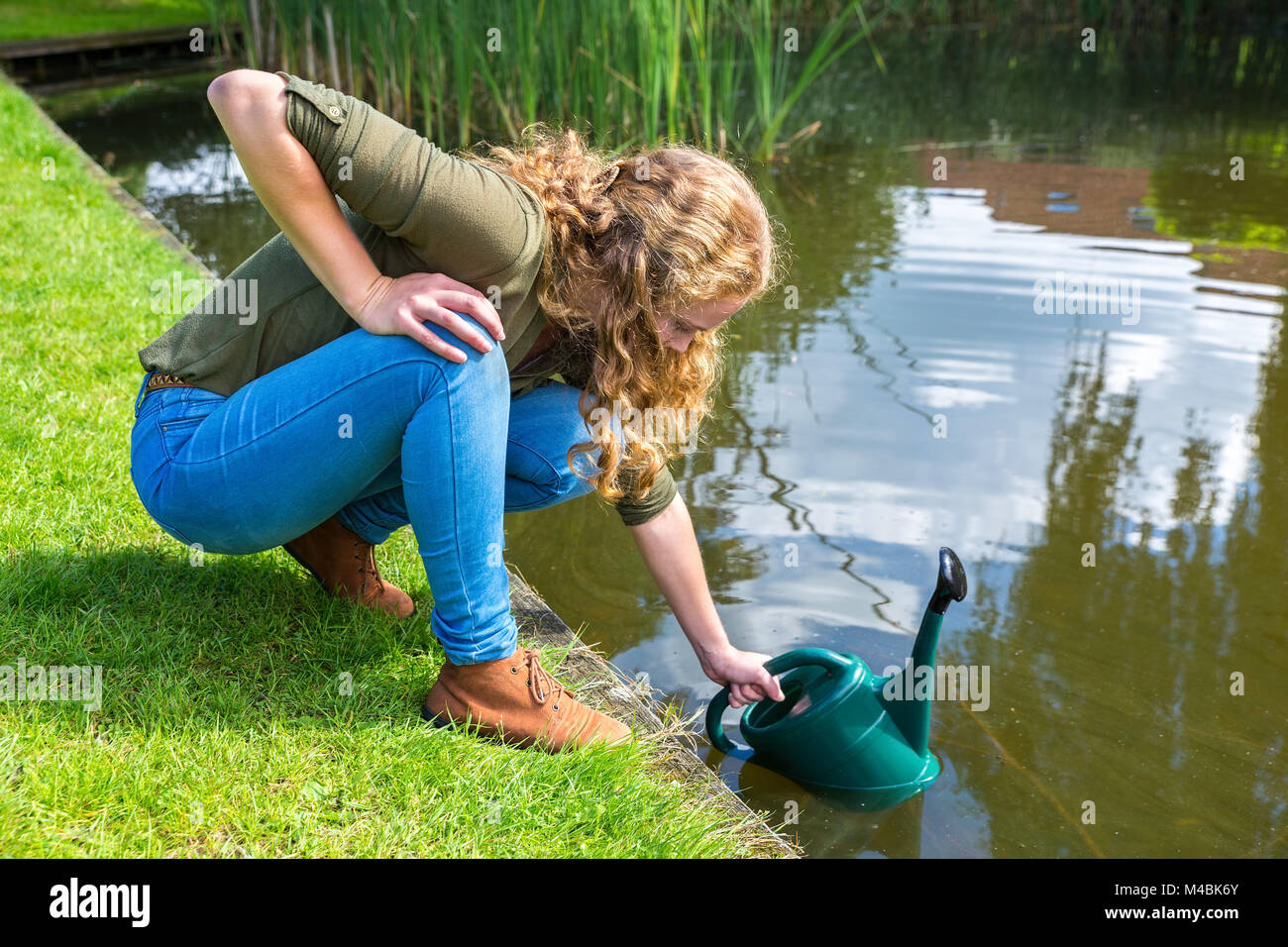 Junge holländische Frau Füllung grün Lenkrolle mit Wasser Stockfoto