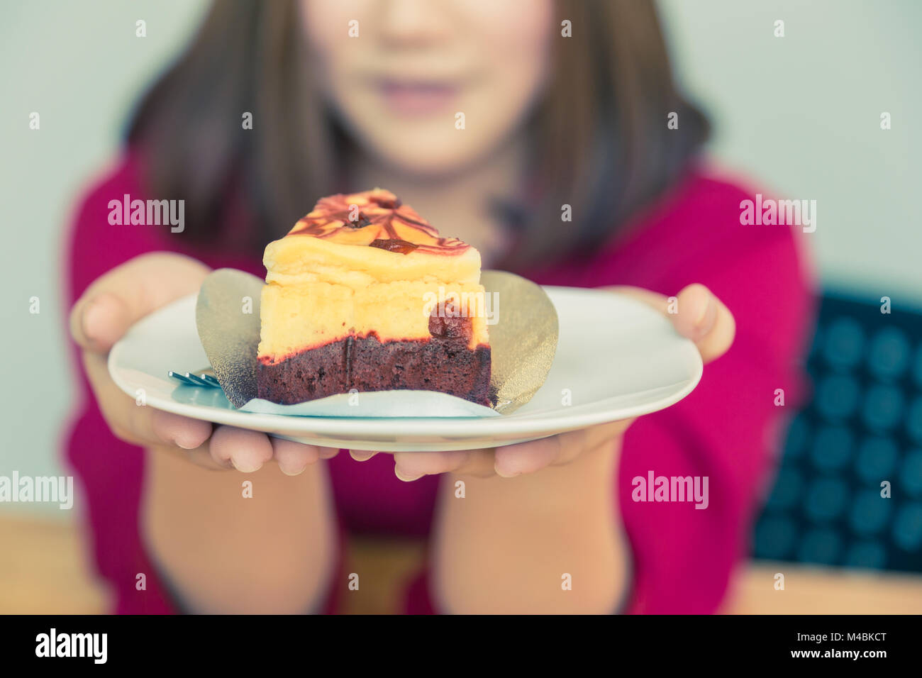 Gerne asiatische Frau mit einem Stück leckeren Kuchen anbieten zu ihrem unsichtbaren Freund, gut zu essen oder Bäckerei Thema, Vintage Retro Farbton, selektive Stockfoto