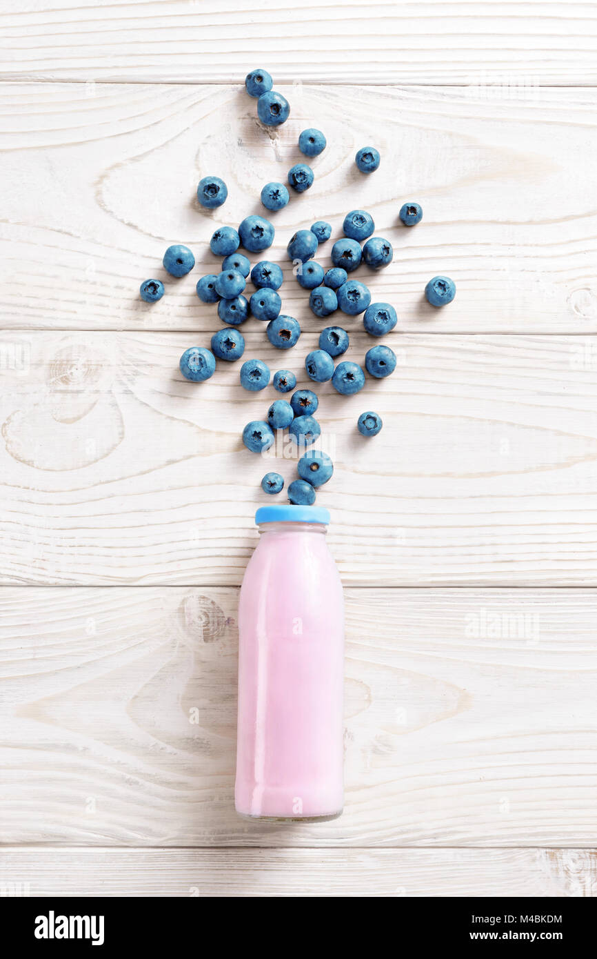Flasche Joghurt mit einer Explosion von Blueberry auf hölzernen Tisch. Frischen Joghurt. Gesunde Ernährung Konzept. Hochauflösende Produkt. Ansicht von oben Stockfoto