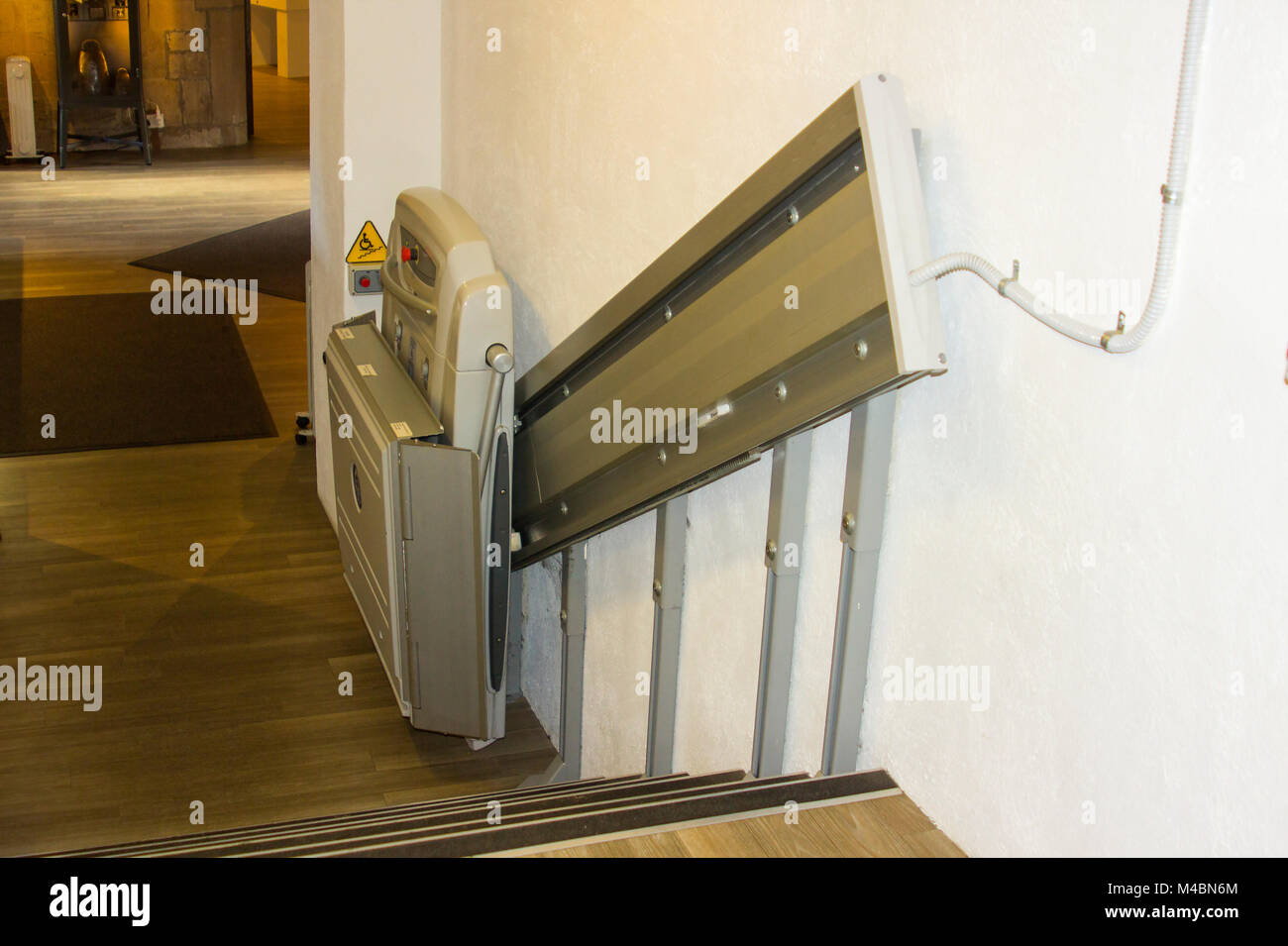 Ein kompaktes Hilfsmittel Unterstützung Treppenlift auf eine kurze Treppe in einem öffentlichen Gebäude in Nordirland Stockfoto