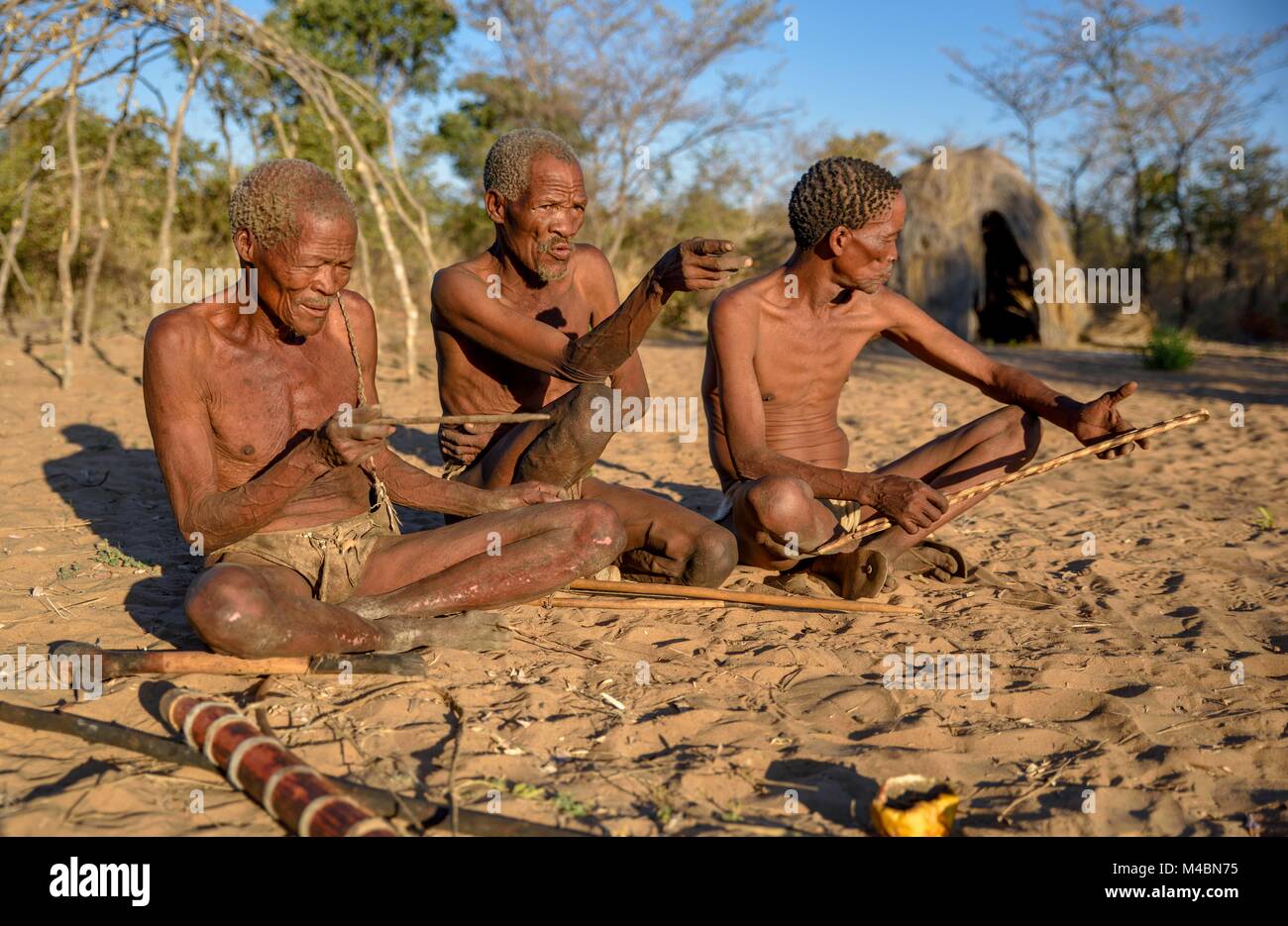 Buschmänner der Ju/'Hoansi-San auf dem Boden sitzend, Dorf //Xa/oba, in der Nähe von Tsumkwe, Otjozondjupa Region, Namibia Stockfoto