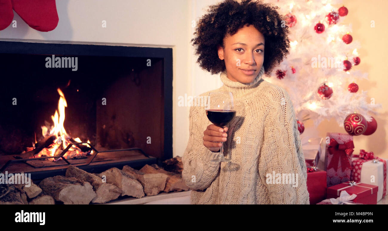 Hübsche Frau hält Glas Wein am Kamin Stockfoto