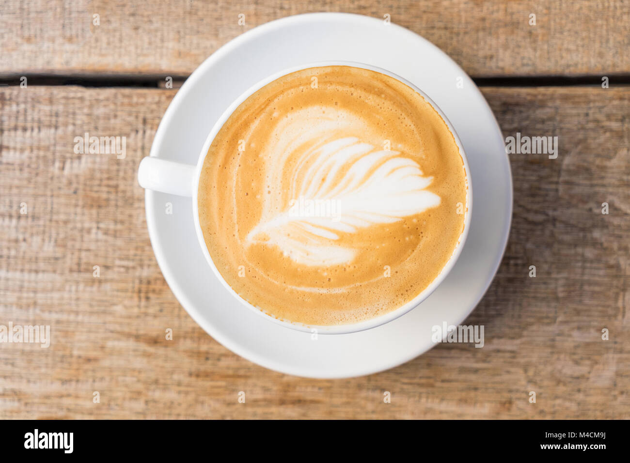 Nahaufnahme einer Tasse Kaffee/Cappuccino mit Schaum und barista Kunst auf Holztisch. Stockfoto