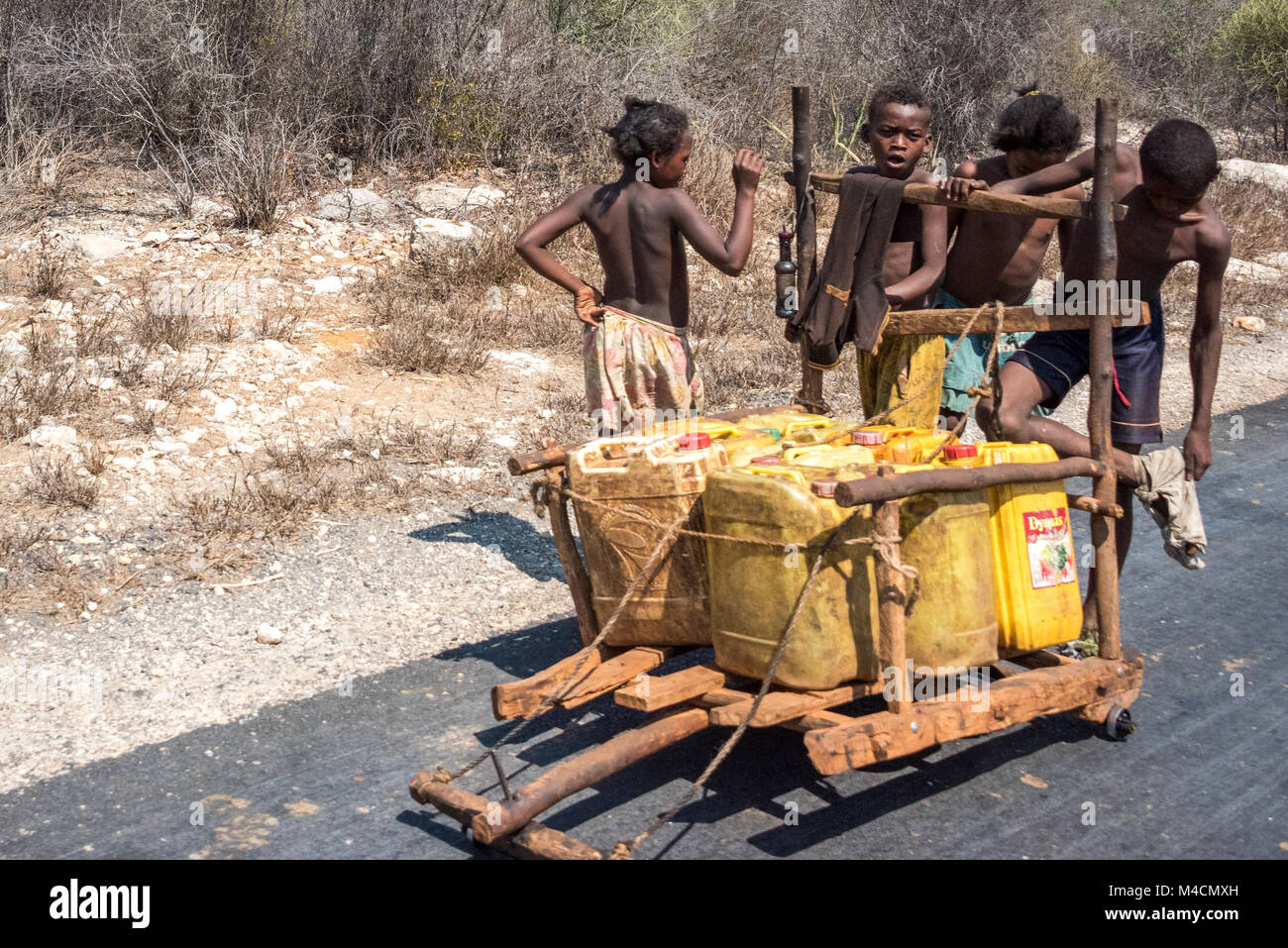 Jungs nach Hause Schieben - gemacht Warenkorb geladen mit Wasser ohne Schuhe, Südliche Madagaskar Stockfoto