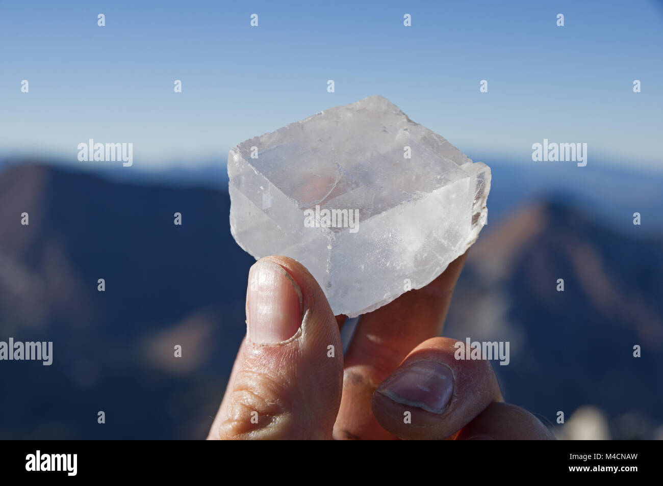 Ein mans hand mit einem calcit Kristall auf einem Berg Stockfoto