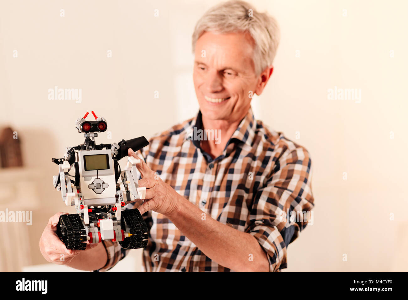 Strahlende Senior Engineer mit Blick auf neue Roboter Maschine Stockfoto