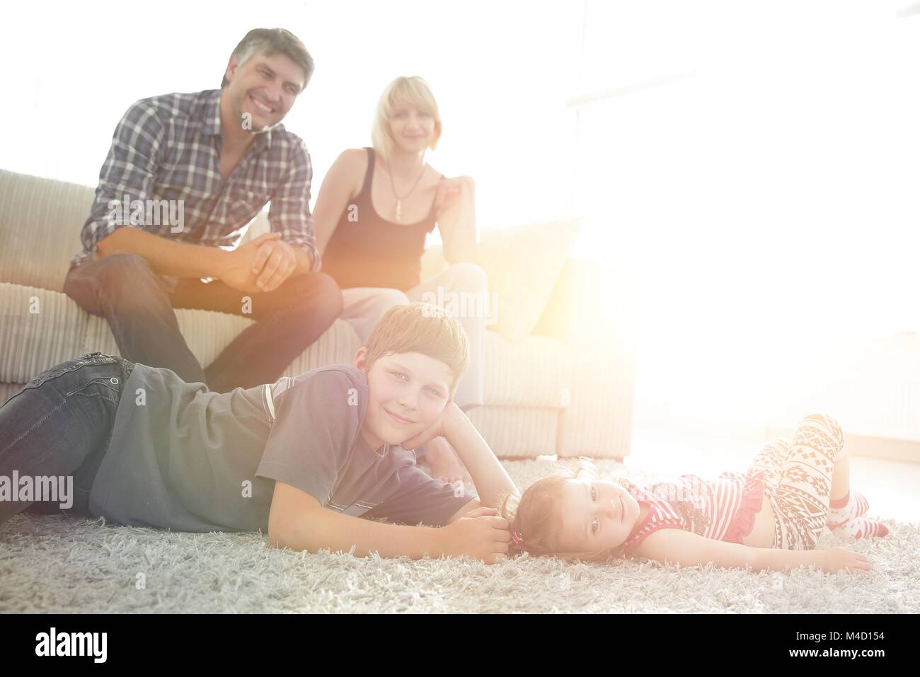 Portrait der Kinder, während die Eltern auf einem Sofa im Wohnzimmer roo Sitzen Stockfoto