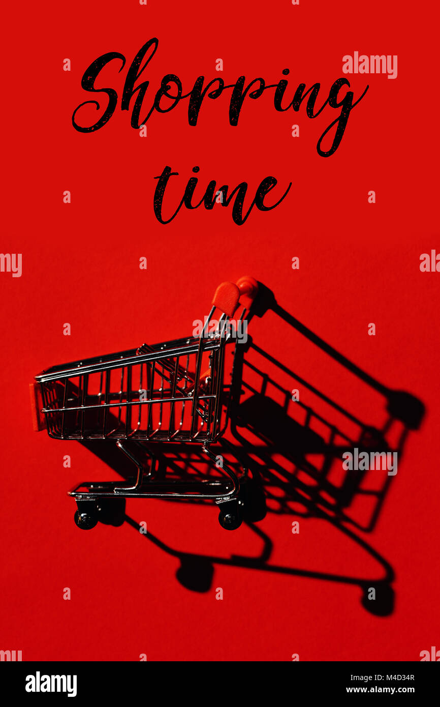 Ein Warenkorb mit Schatten auf rote Wand und Worte Shopping Zeit Stockfoto