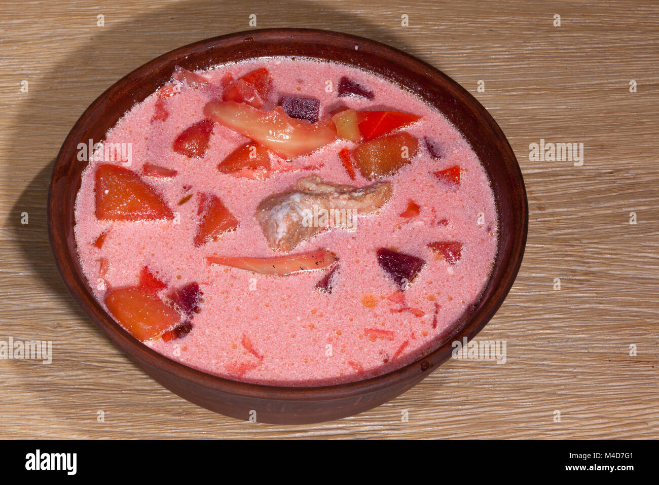 Die Nationalen Ukrainischen essen - borschtsch mit saurer Sahne mit einem Holzlöffel in einem Ton Platte auf einer Eiche Tisch Stockfoto