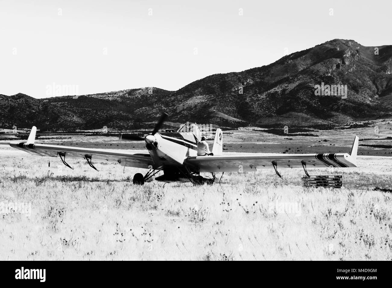 Eine gelbe seeder Flugzeug in der Wüste von Utah gelandet mit dem Piloten sitzen auf dem Flügel in Schwarz und Weiß. Stockfoto