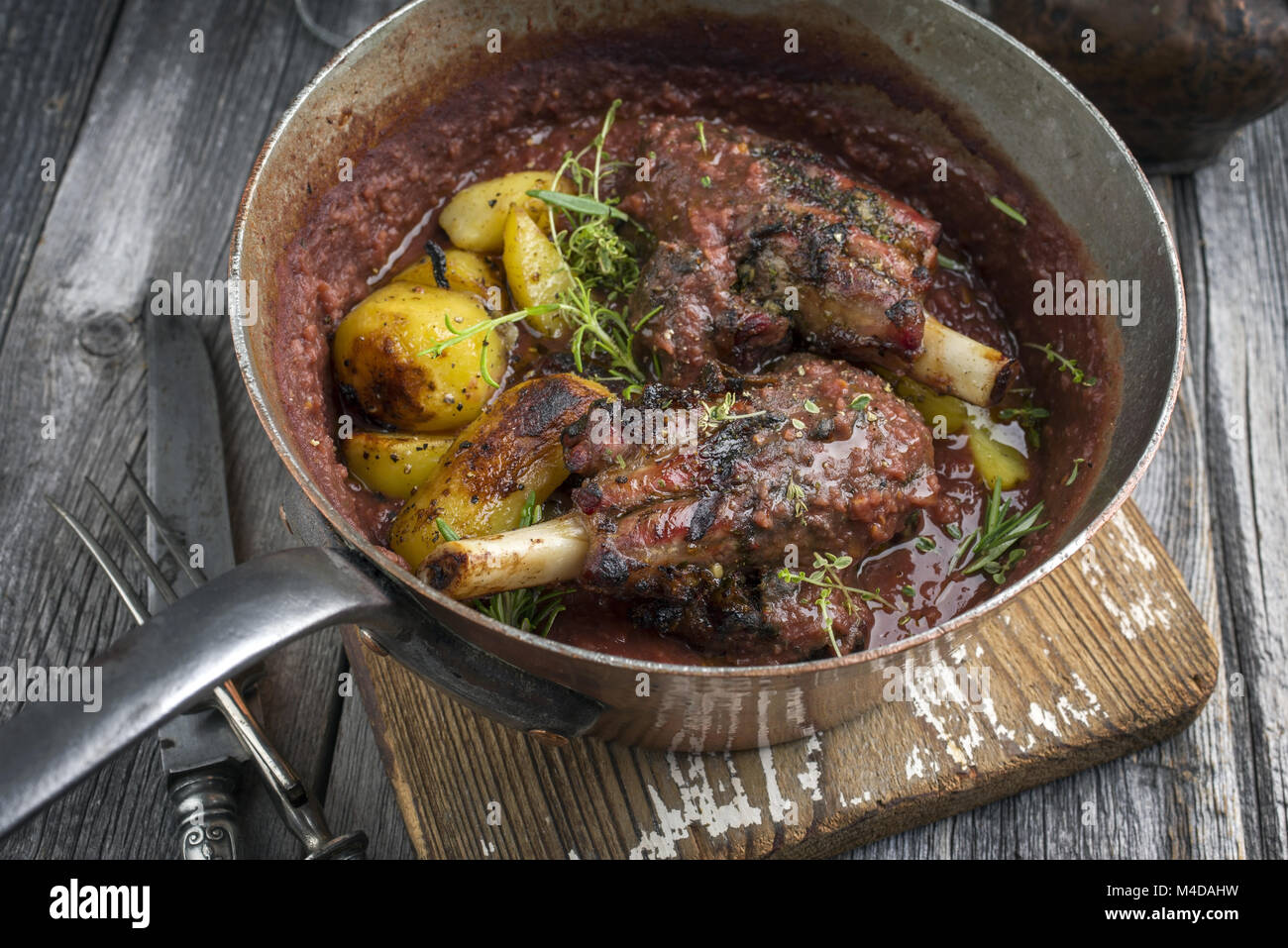 Lamm Knuckles mit Kartoffeln in Burgund Soße in Kasserolle Stockfoto