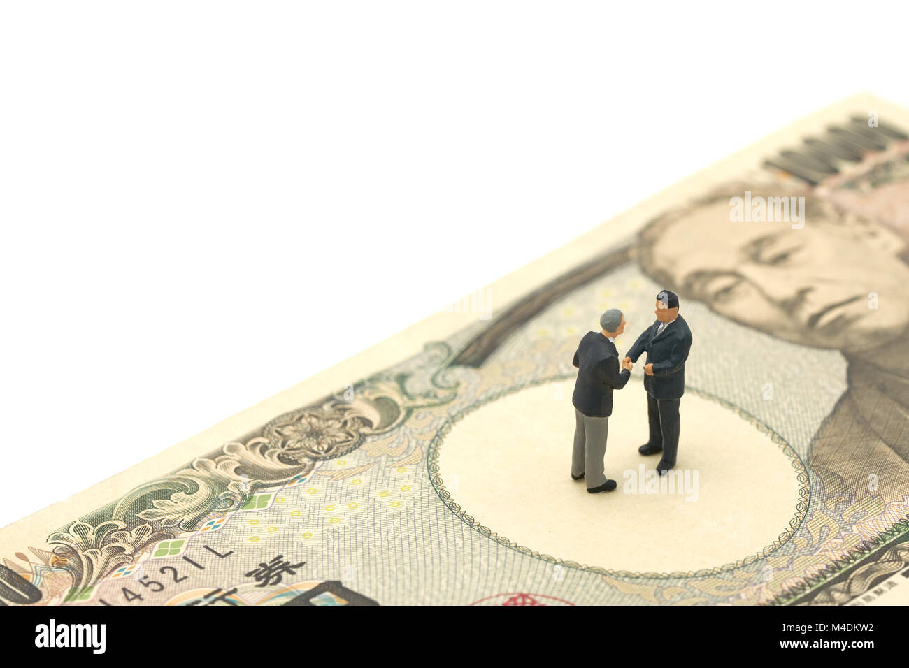 Miniatur 2 Personen Unternehmer Hände schütteln Stehen auf japanischen Banknoten im Wert von 10.000 Yen als Hintergrund Business Konzept und Finanzierung Konzept mit Stockfoto