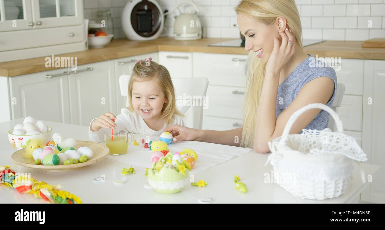 Lachende Frau und kleines Mädchen färben Eier Stockfoto