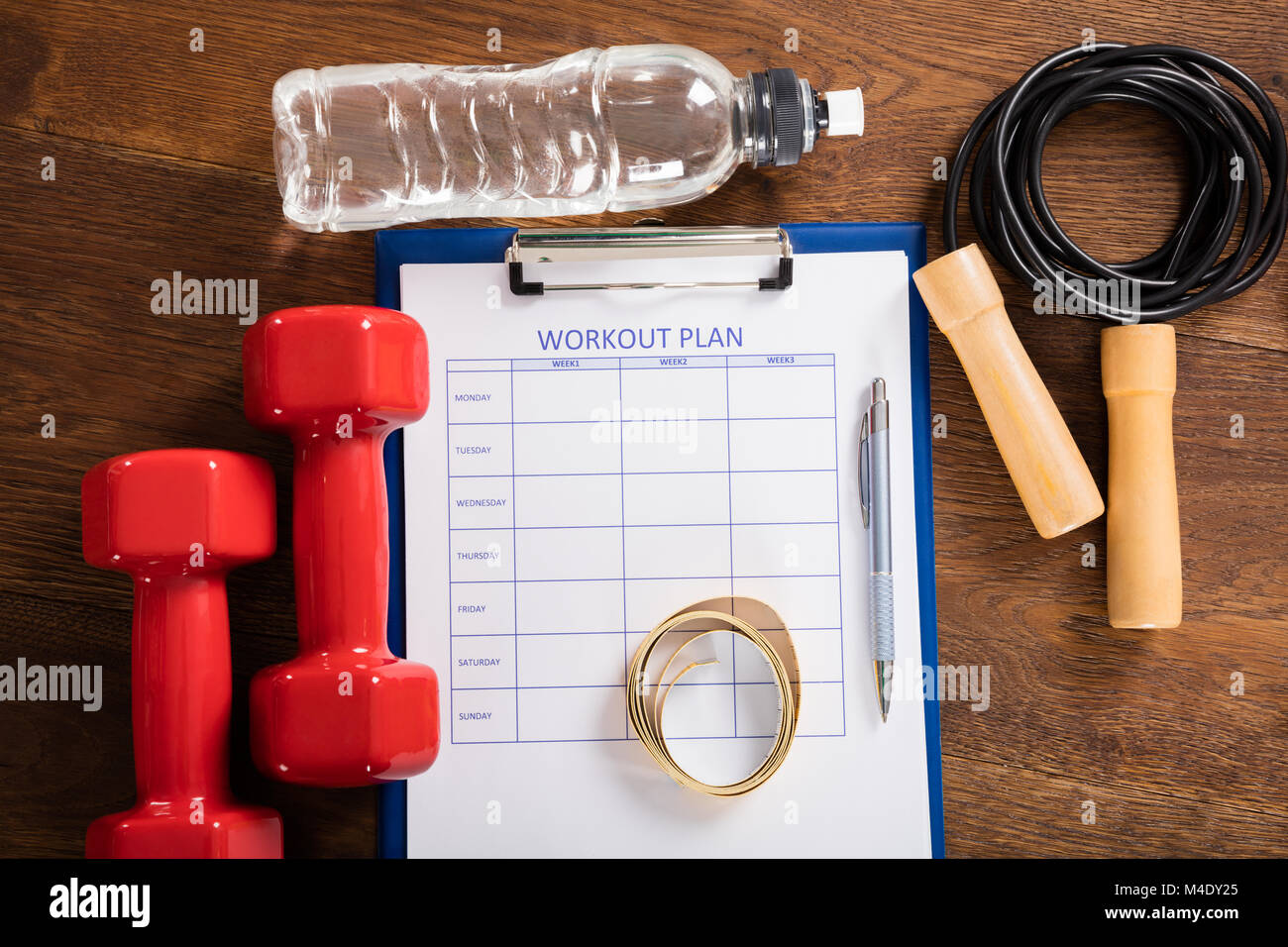 Hohe Betrachtungswinkel von Workout Plan Form mit Fitnessgeräte am Schreibtisch Stockfoto