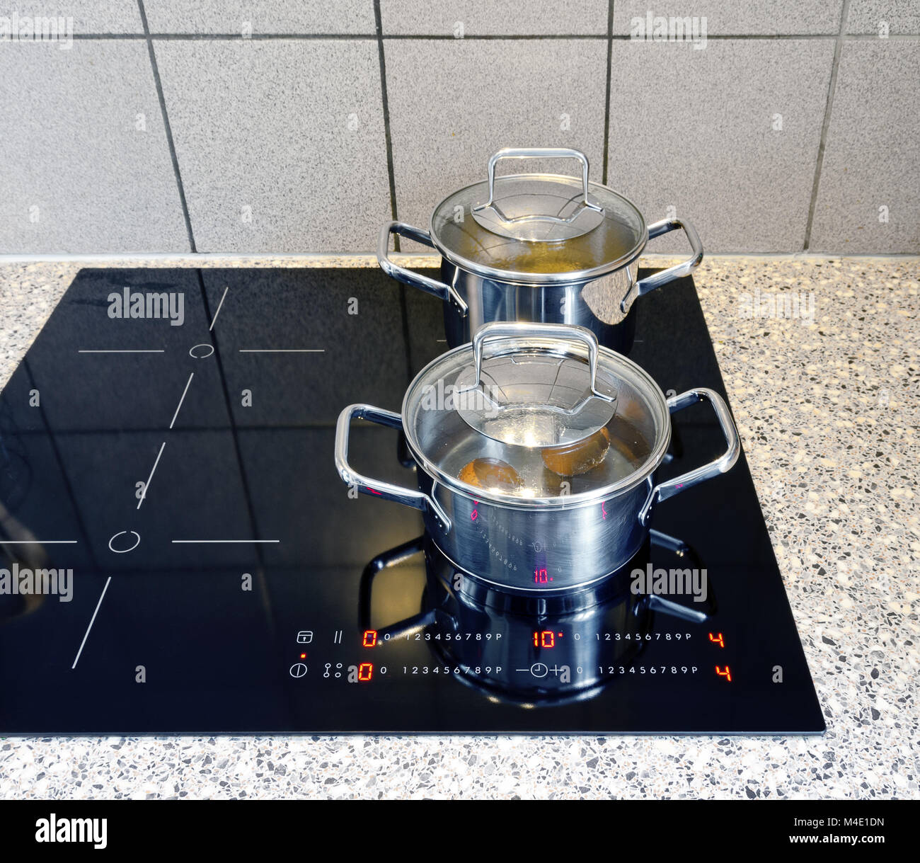Kochtöpfe auf einem modernen schwarzen Glaskeramik-Kochfläche Stockfoto