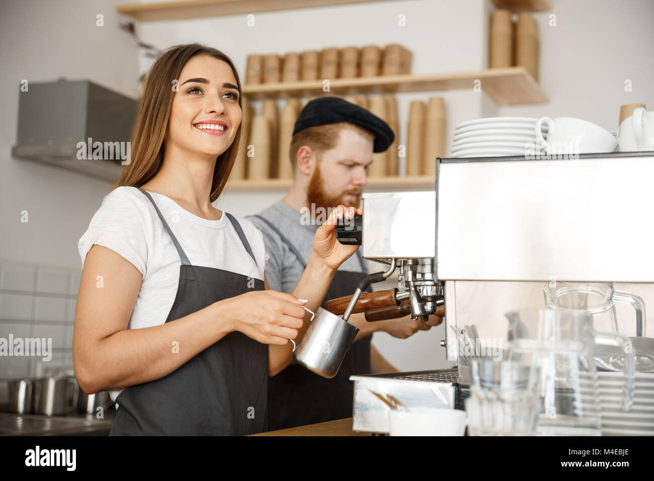 Kaffee Geschäftskonzept - Porträt der Lady Barista im Vorfeld vorbereiten und dampfende Milch für den Kaffee, um mit Ihrem Partner, während im Cafe. Stockfoto