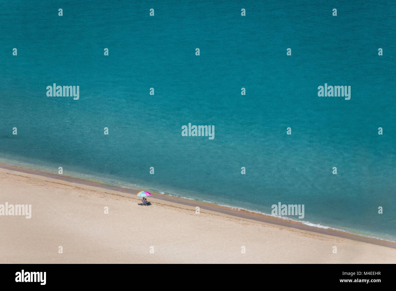 Ältere Frau am Strand unter einem Sonnenschirm, Waimea Bay, Oahu, Hawaii, USA Stockfoto