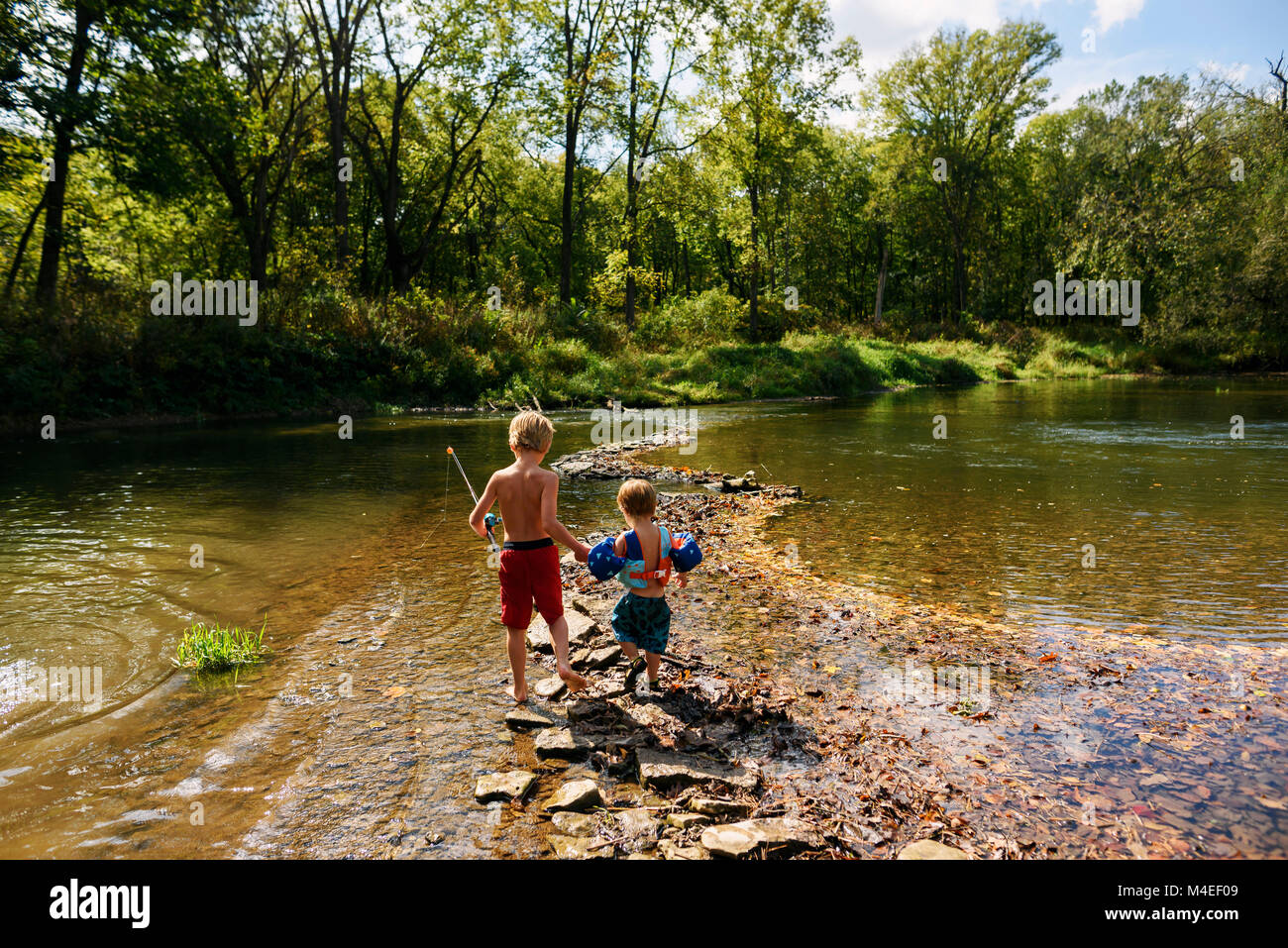 Zwei Jungen, die einen Fluß überquert, Fischen zu gehen Stockfoto