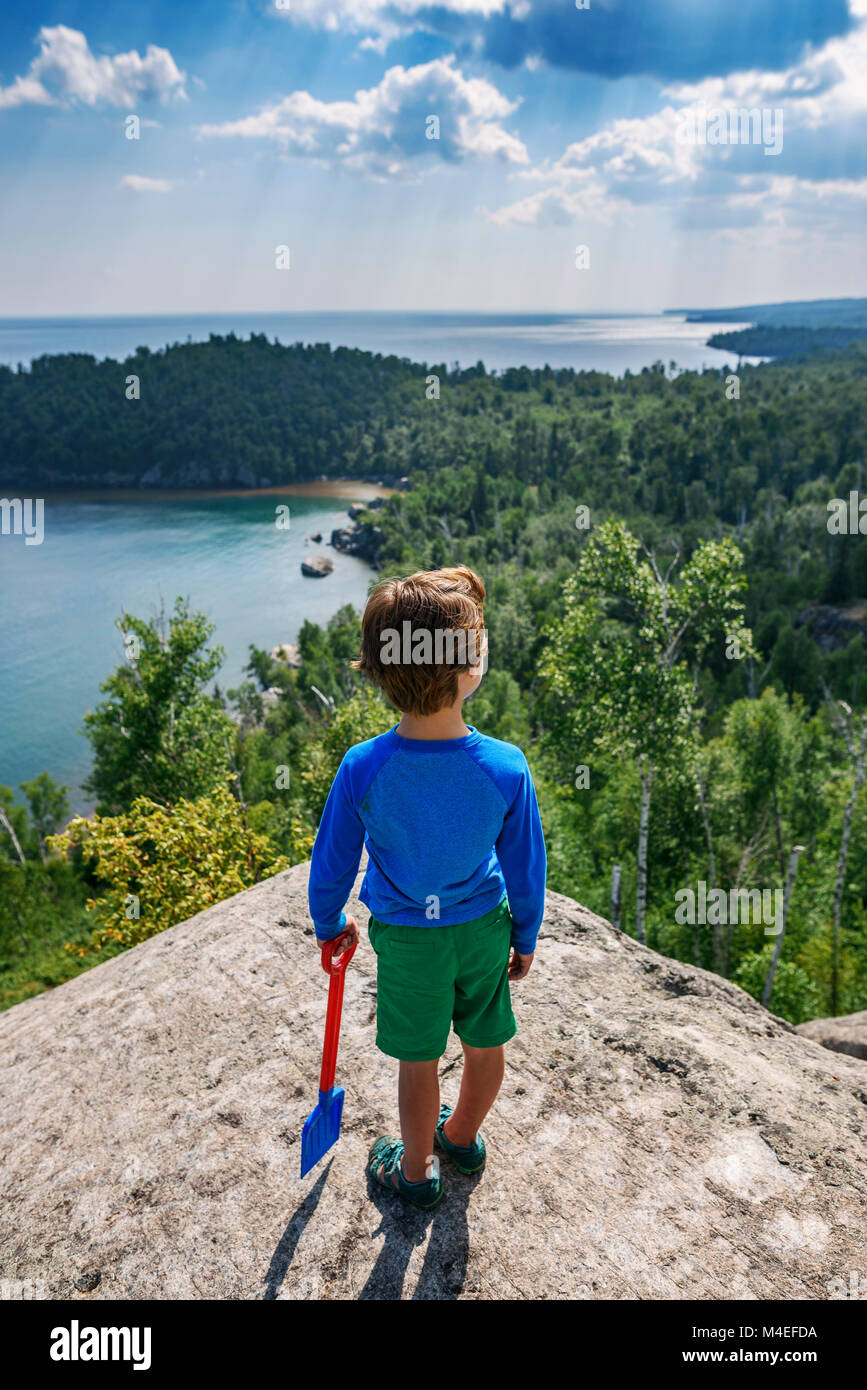 Junge stehend auf einem Felsen an der Küste Blick nach unten schauen. Stockfoto