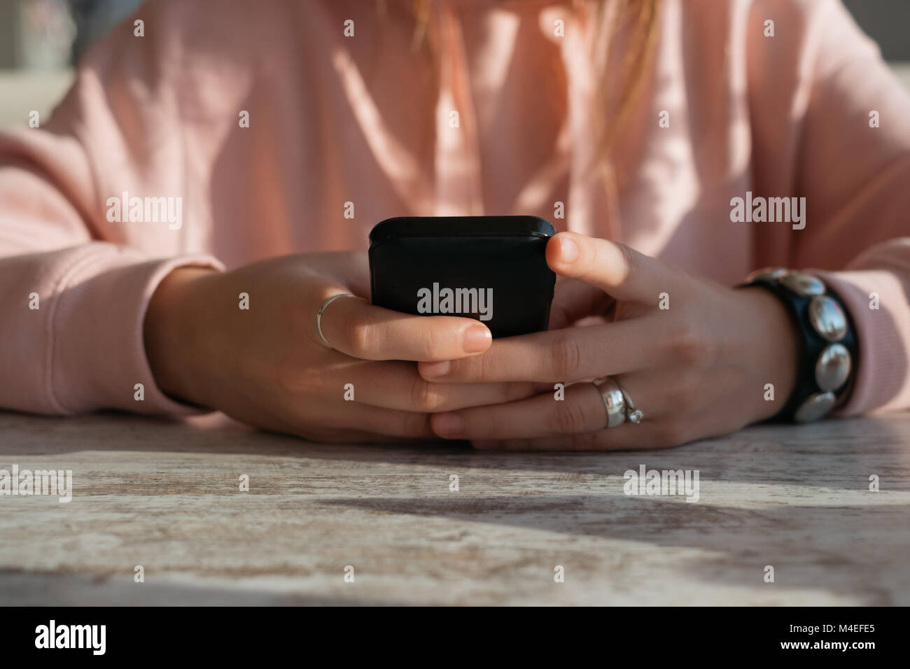 Frau sitzt an einem Tisch mit einem Mobiltelefon Stockfoto