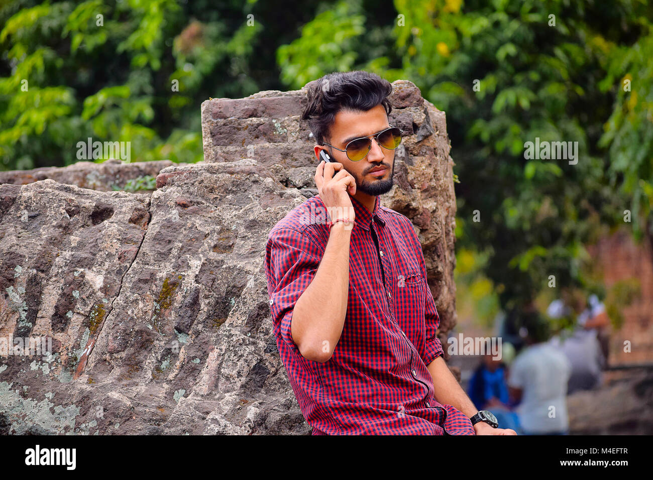 Junger Mann mit kariertes Hemd am Handy, Pune, Maharashtra. Stockfoto