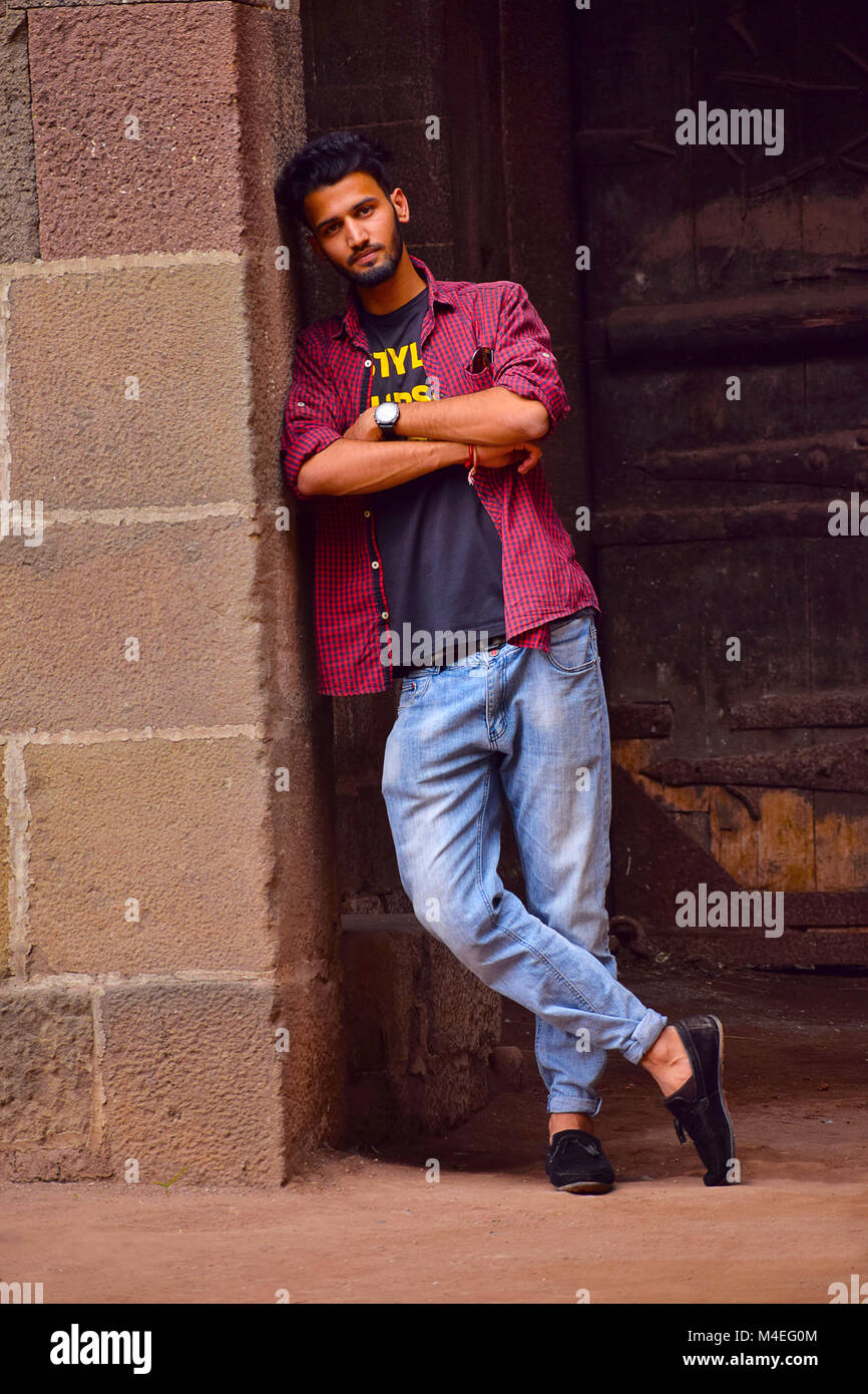 Junger Mann mit kariertes Hemd lehnte sich an der Wand, Pune, Maharashtra. Stockfoto