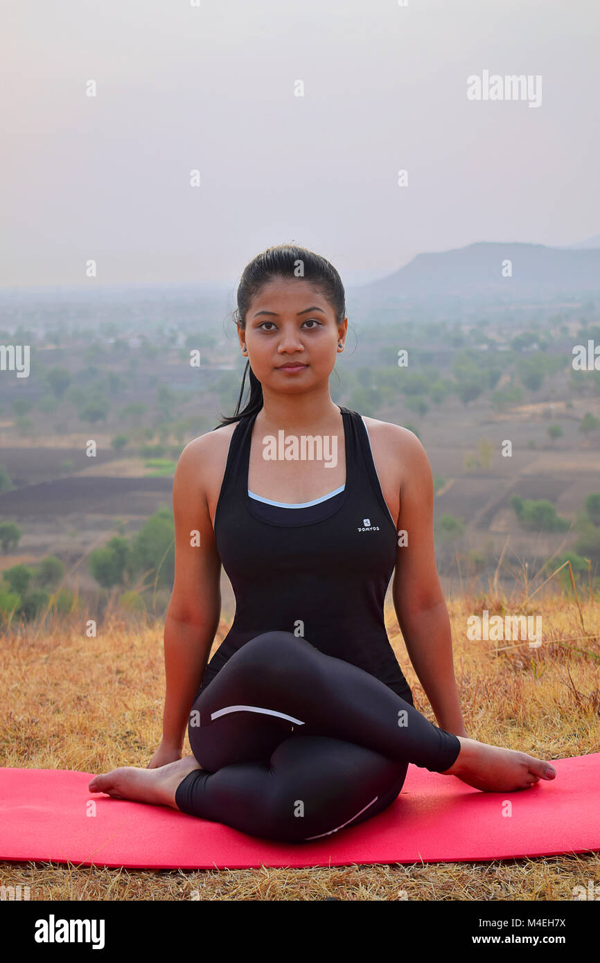 Junge indische Mädchen tun Fitness Übungen mit Bergkulisse, Pune, Maharashtra. Stockfoto