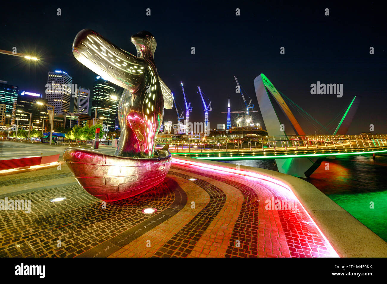 Perth, Australien - Jan 5, 2018: Der erste Kontakt Skulptur im Vordergrund Elizabeth Quay Marina am Abend beleuchtet. Baukräne und Arcade der Elizabeth Quay Brücke im Hintergrund. Stockfoto