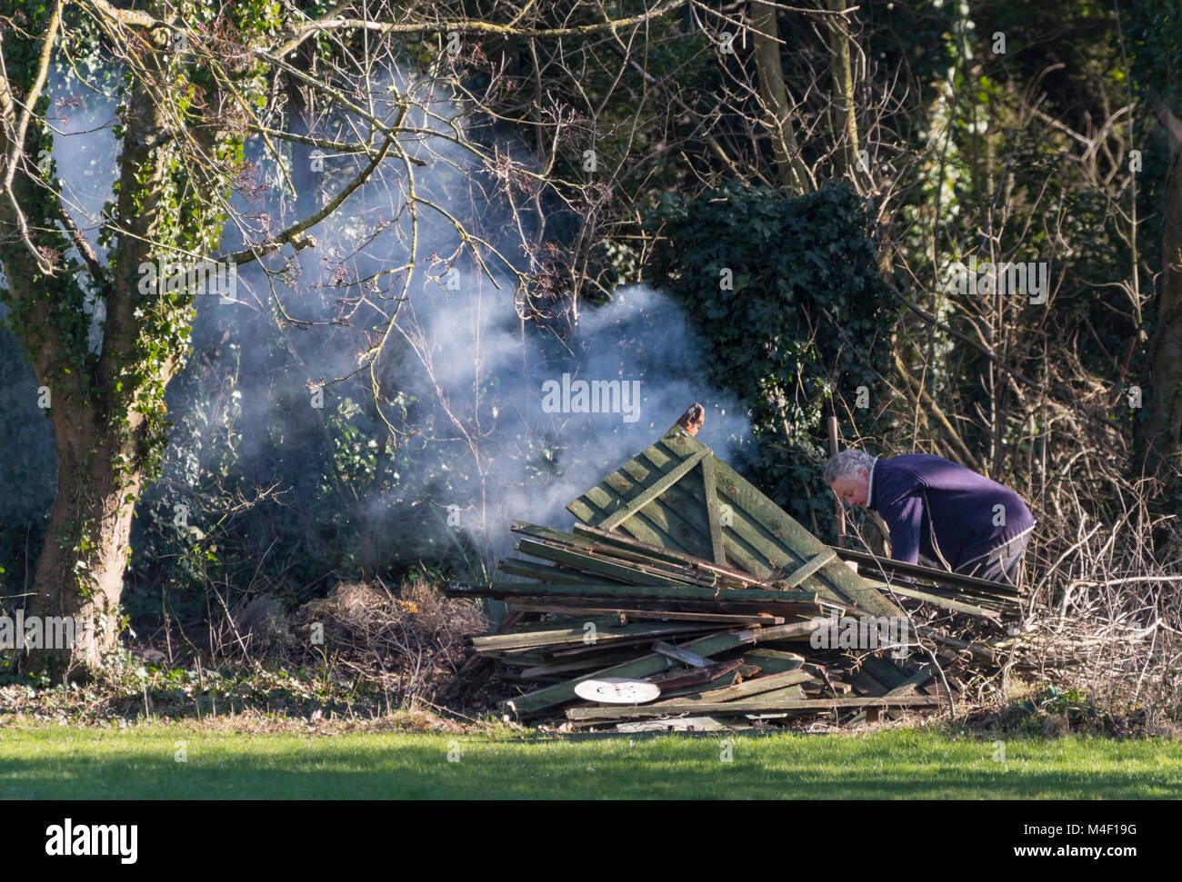 Mann an einem Lagerfeuer Verbrennen von Holz und Abfall im Winter in England, Großbritannien. Stockfoto
