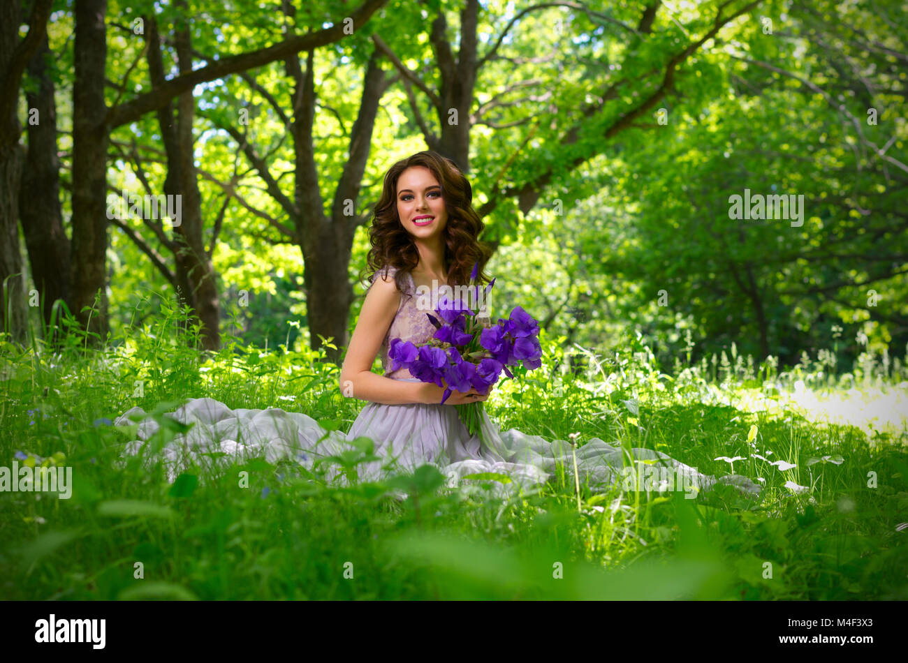 Junge Frau mit Blumen im Wald (ohne Sonnenstrahlen ver) Stockfoto