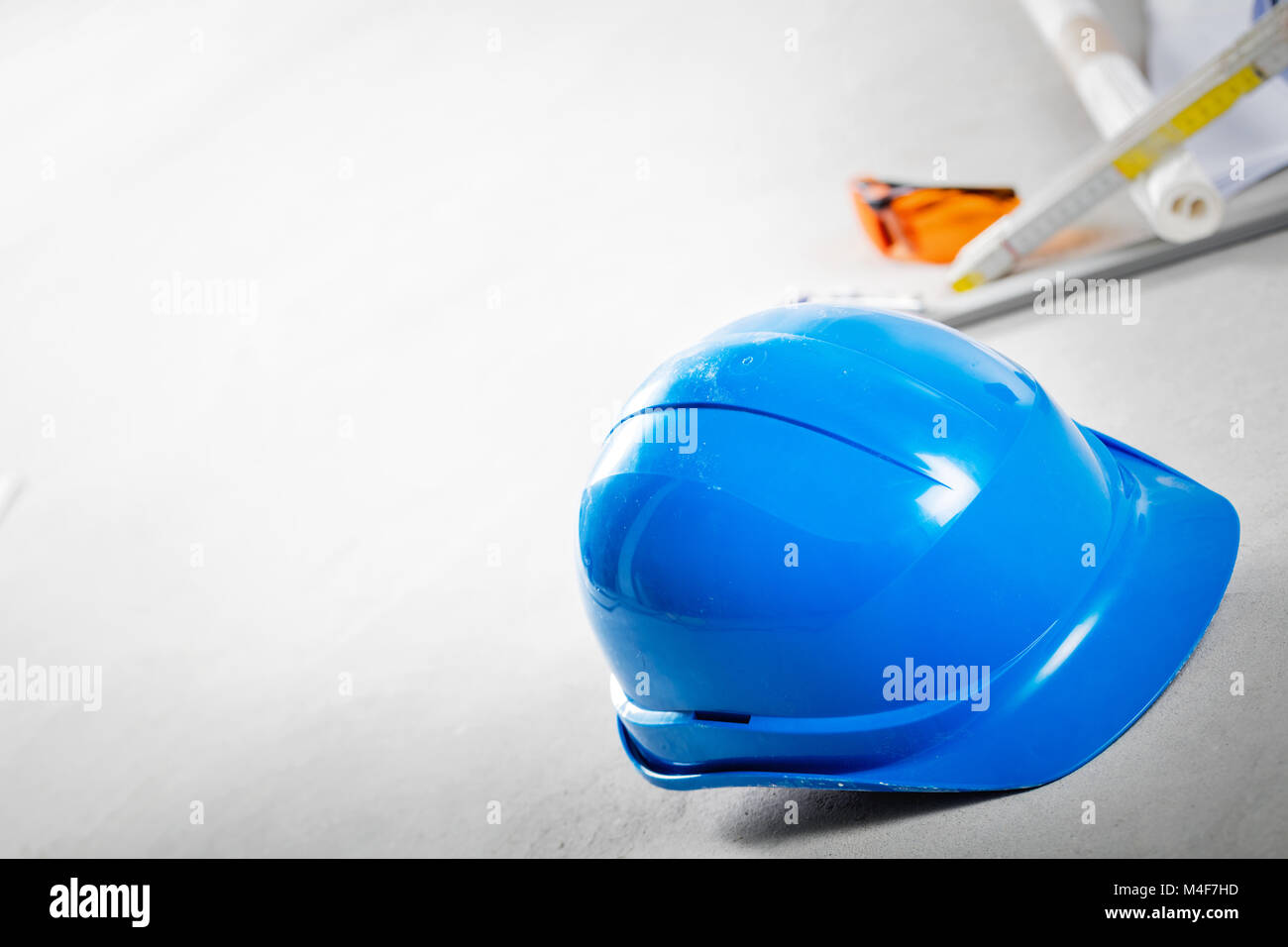 Schutzhelm, Schutzbrille und Blueprints auf Baustelle. Stockfoto