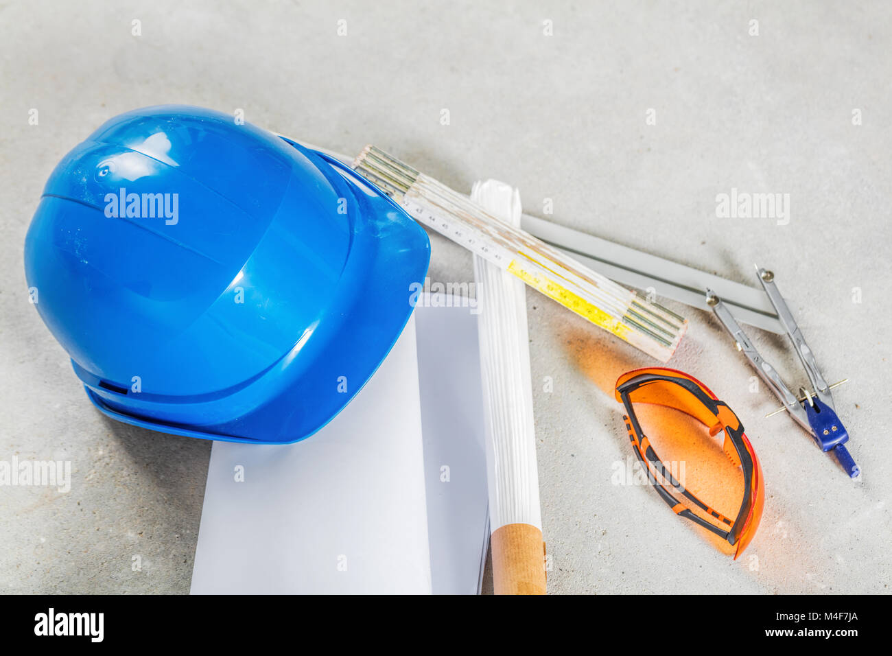 Schutzhelm, Schutzbrille und Blueprints auf Baustelle. Stockfoto