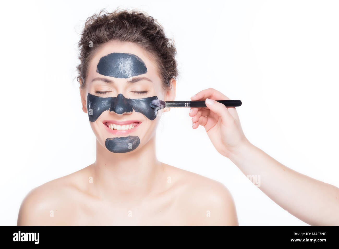 Black Charcoal Maske Anwendung auf schöne Frau. Stockfoto