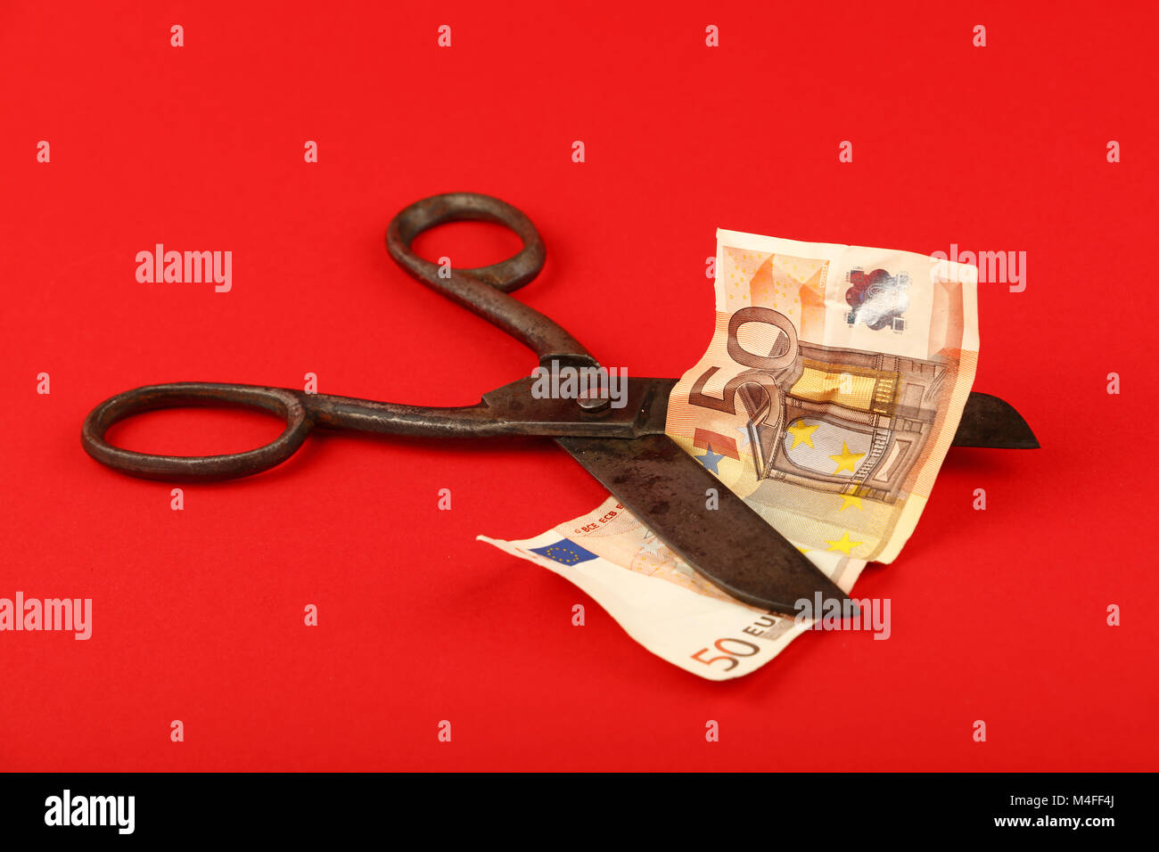 Europa Finanzkrise, Rückgang der europäischen Wirtschaft und Euro Wechselkurs illustrierte, alte Vintage Schere schneiden 50 Euro-Banknote auf rotem Grund Stockfoto