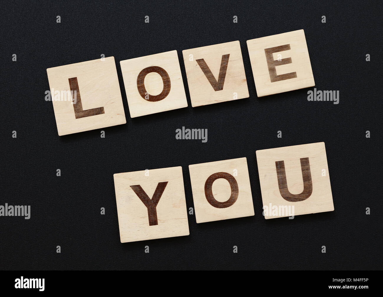 Close up Worte LIEBE SIE auf Holz schreiben Zeichen über schwarzen Brett Hintergrund Stockfoto