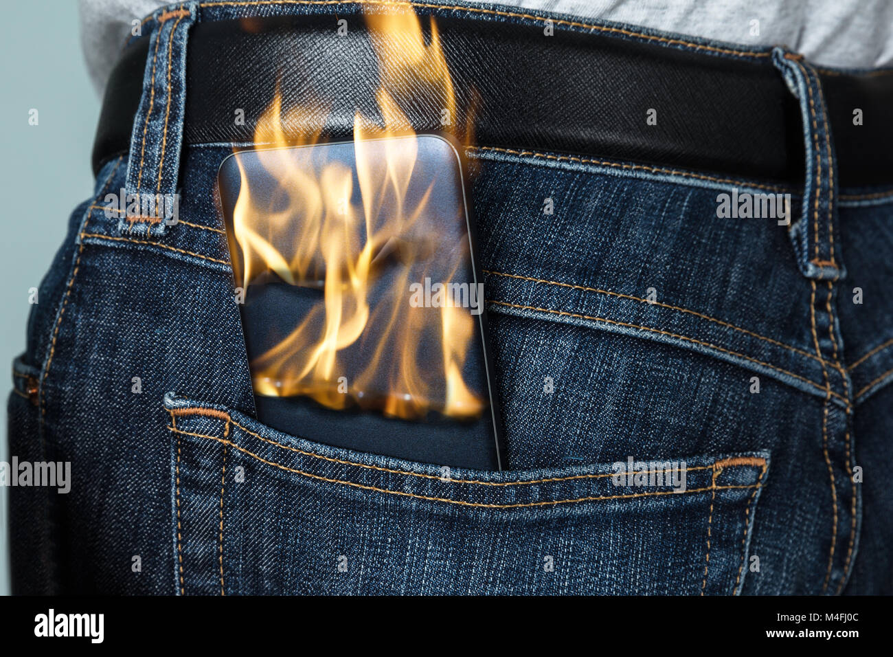 Nahaufnahme eines brennenden Telefon in der Gesäßtasche der Jeans Stockfoto