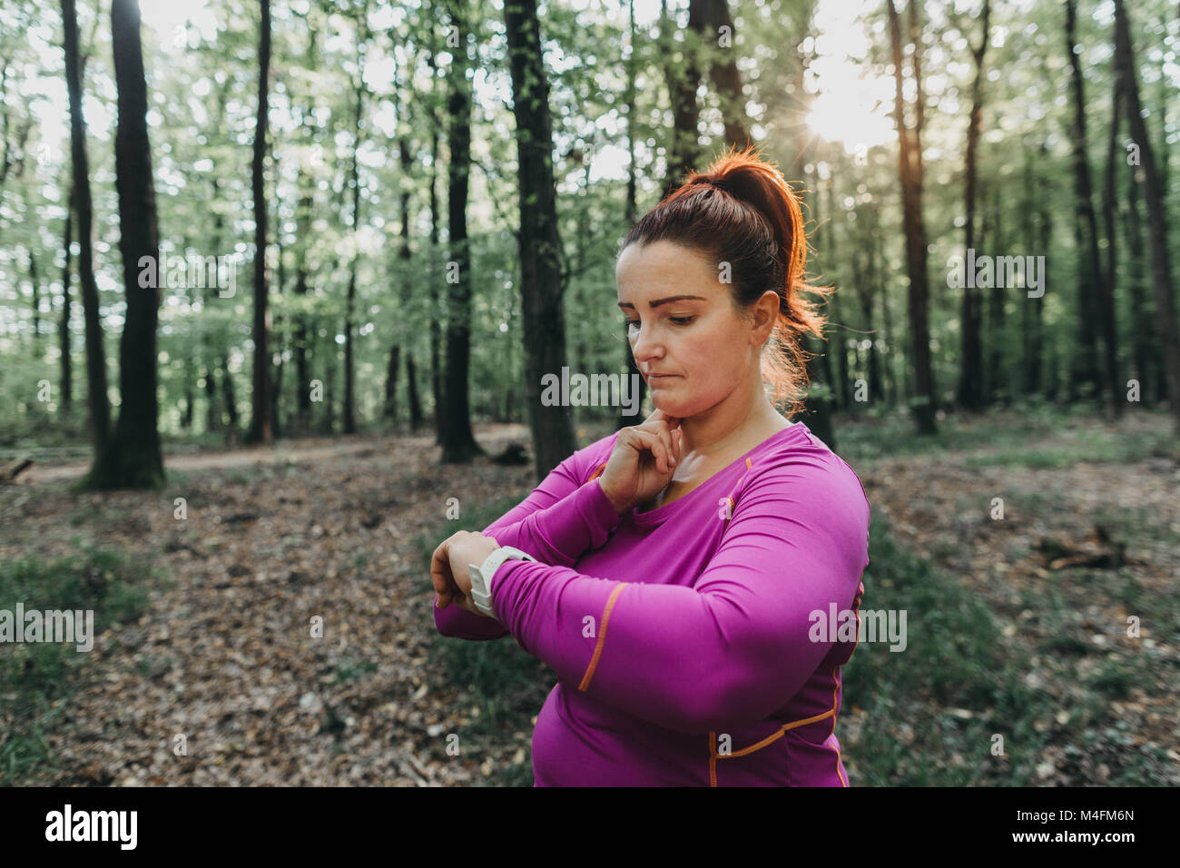Porträt einer plus Größe weibliche Jogger ihr Puls Messung nach einem Jog in einem Park. Stockfoto