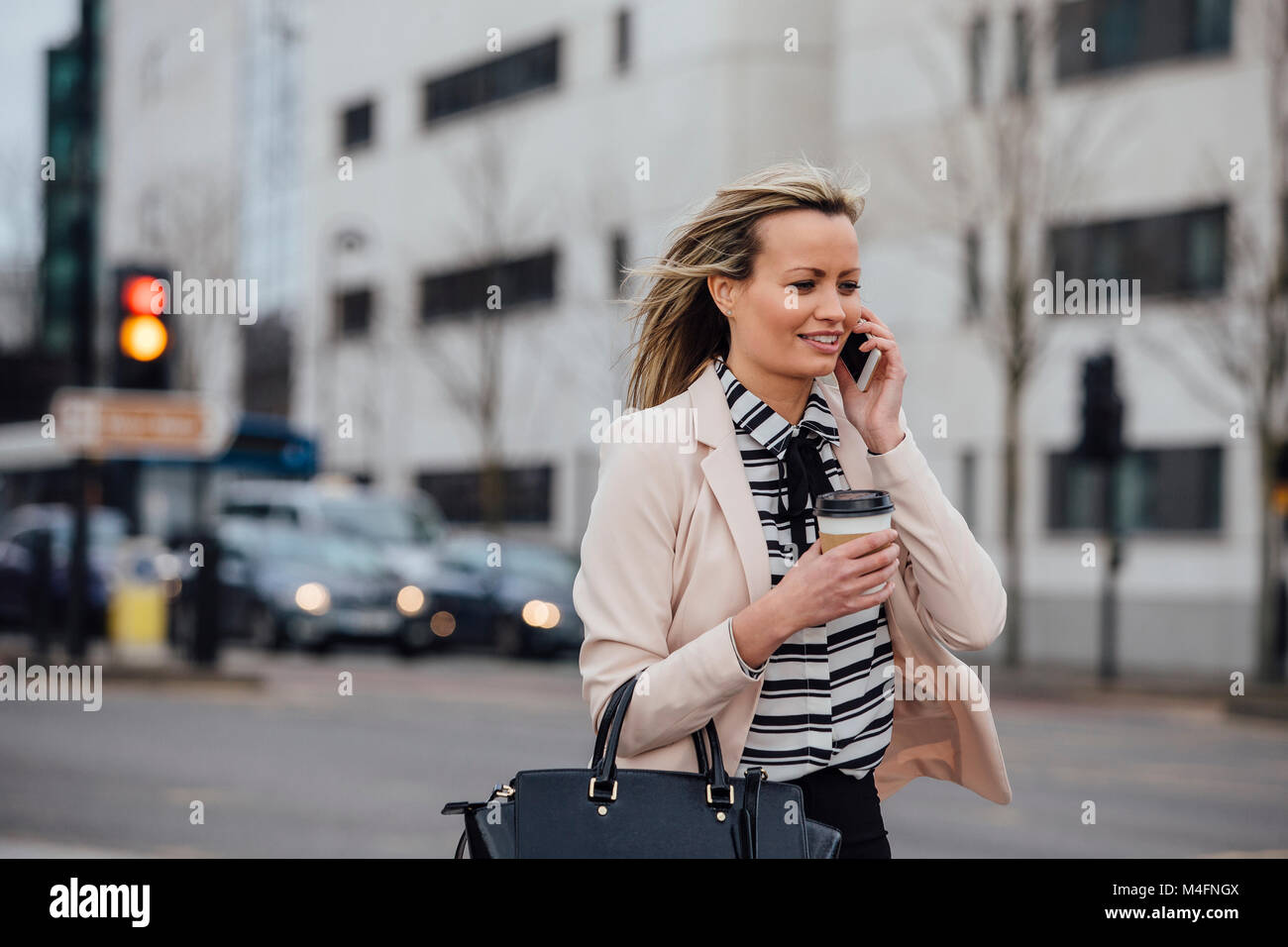 Geschäftsfrau ist zu Fuß in der Stadt zu arbeiten. Sie hält eine Kaffeetasse und ist, am Telefon zu sprechen. Stockfoto