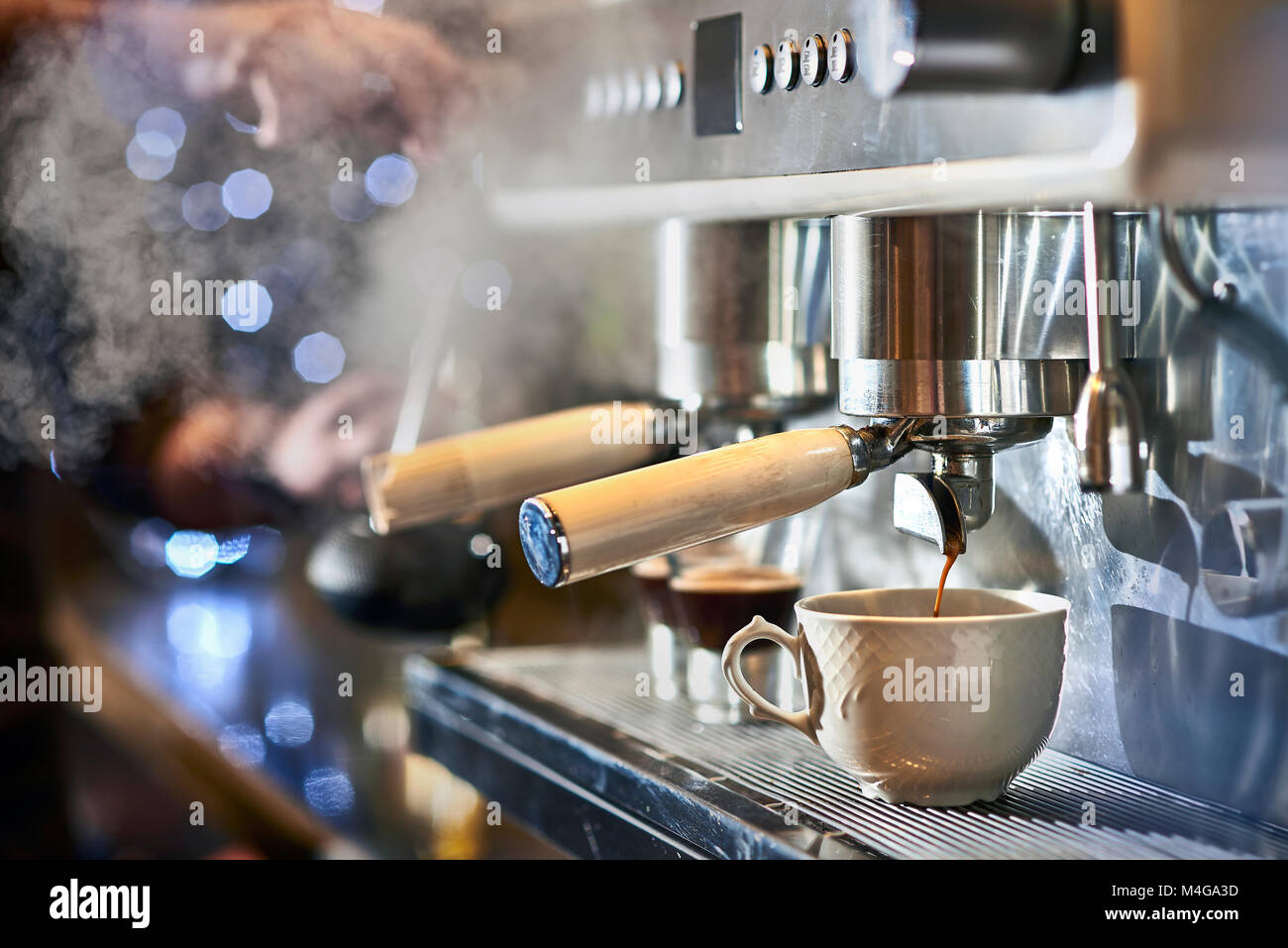 Barista, einen Espresso mit einem klassischen italienischen Kaffee Maschine mit Dampf im Hintergrund. Stockfoto