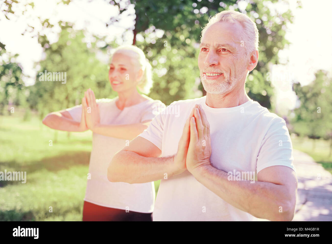 Positive ältere Freunde in Meditation im Freien Stockfoto